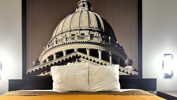 Een bed met een groot poster van de koepel en zuilen van een statig gebouw.