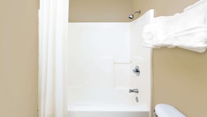 Een kleine, witte badkamer met een douche, een wastafel en een handdoek aan de muur.
