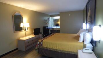 Una habitación de hotel con cama, mesita de noche, lámpara, televisor y espejo.