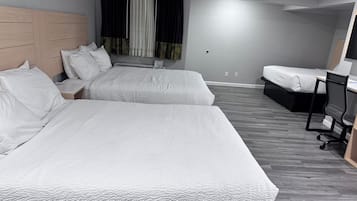 A hotel room with two beds, a desk, a chair, and a window with curtains.