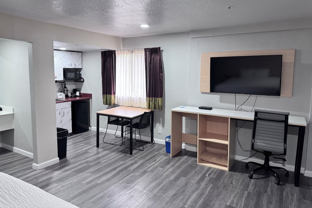Une chambre moderne Ă©quipĂ©e dâun bureau, dâune chaise, dâune tĂ©lĂ©vision et dâune kitchenette.