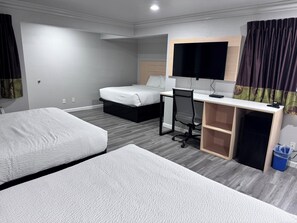 A hotel room with two beds, a desk, a chair, a TV, and a small trash bin. - Travelodge by Wyndham Redding CA (Redding)