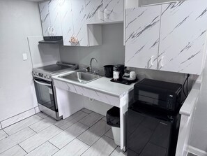 A modern kitchen with a built-in oven, a microwave, a sink, and a coffee maker. - Travelodge by Wyndham Redding CA (Redding)