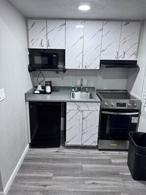 Cocina compacta equipada con microondas, fregadero, horno y lavavajillas.