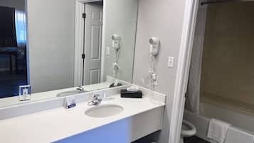 A bathroom with a white sink, mirror, and a hairdryer on the wall.