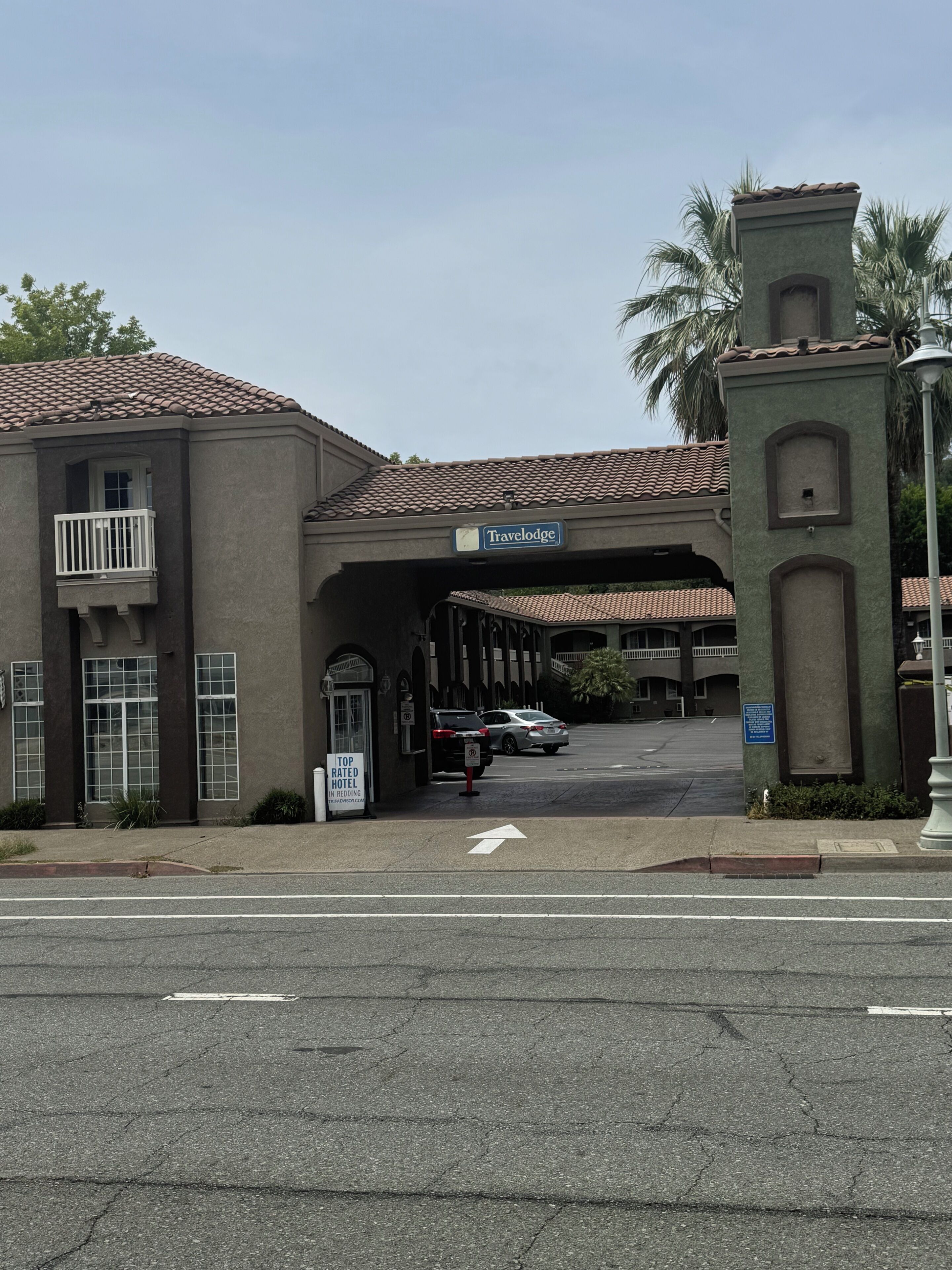 A Travelodge hotel with a tiled roof, a balcony, and a sign indicating it is a top-rated hotel in the region.