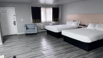 A hotel room with two beds, a sofa, a desk, and a window with curtains.