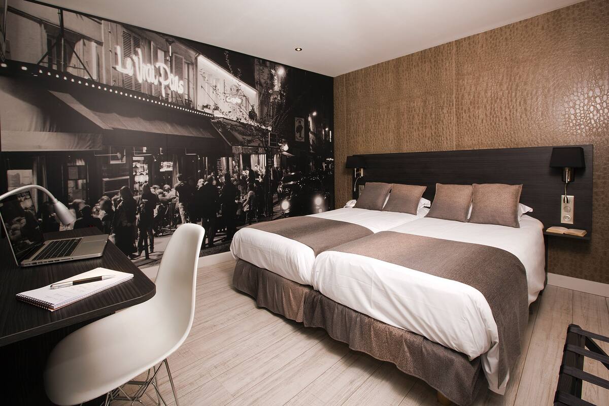 Une chambre d’hôtel moderne, dotée d’un grand lit, d’un bureau avec un ordinateur portable et d’une chaise.