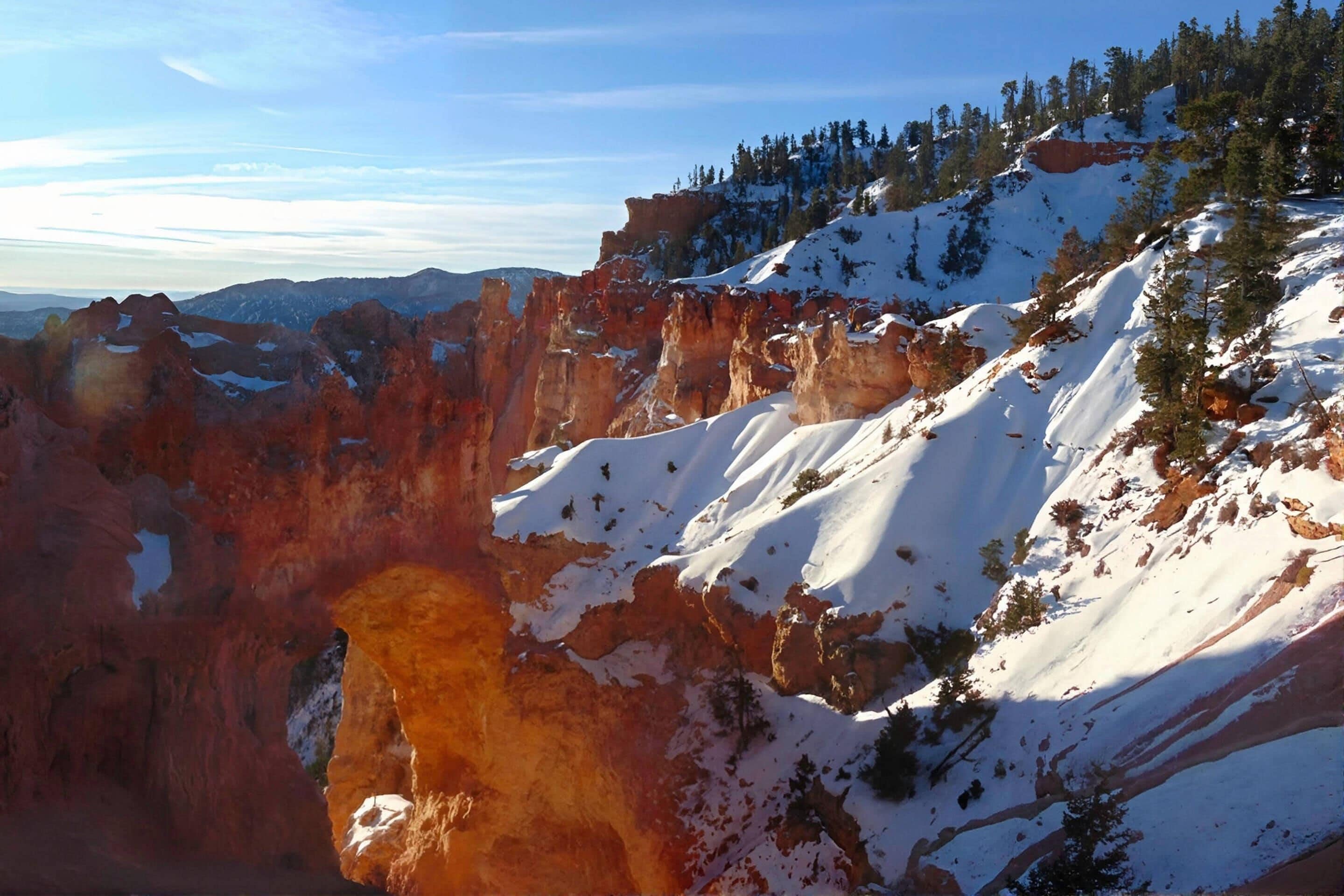 A canyon with snow-covered cliffs and sparse vegetation.