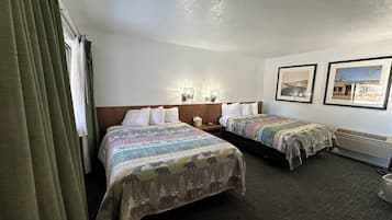 A hotel room with two beds, a nightstand, a wall-mounted lamp, and framed pictures on the wall.