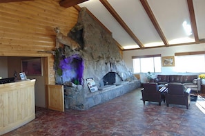 A stone fireplace with a lion statue, a wooden ceiling, a stone wall, a wooden counter, and a seating area with leather chairs. - Bryce Canyon Resort (Bryce Canyon)