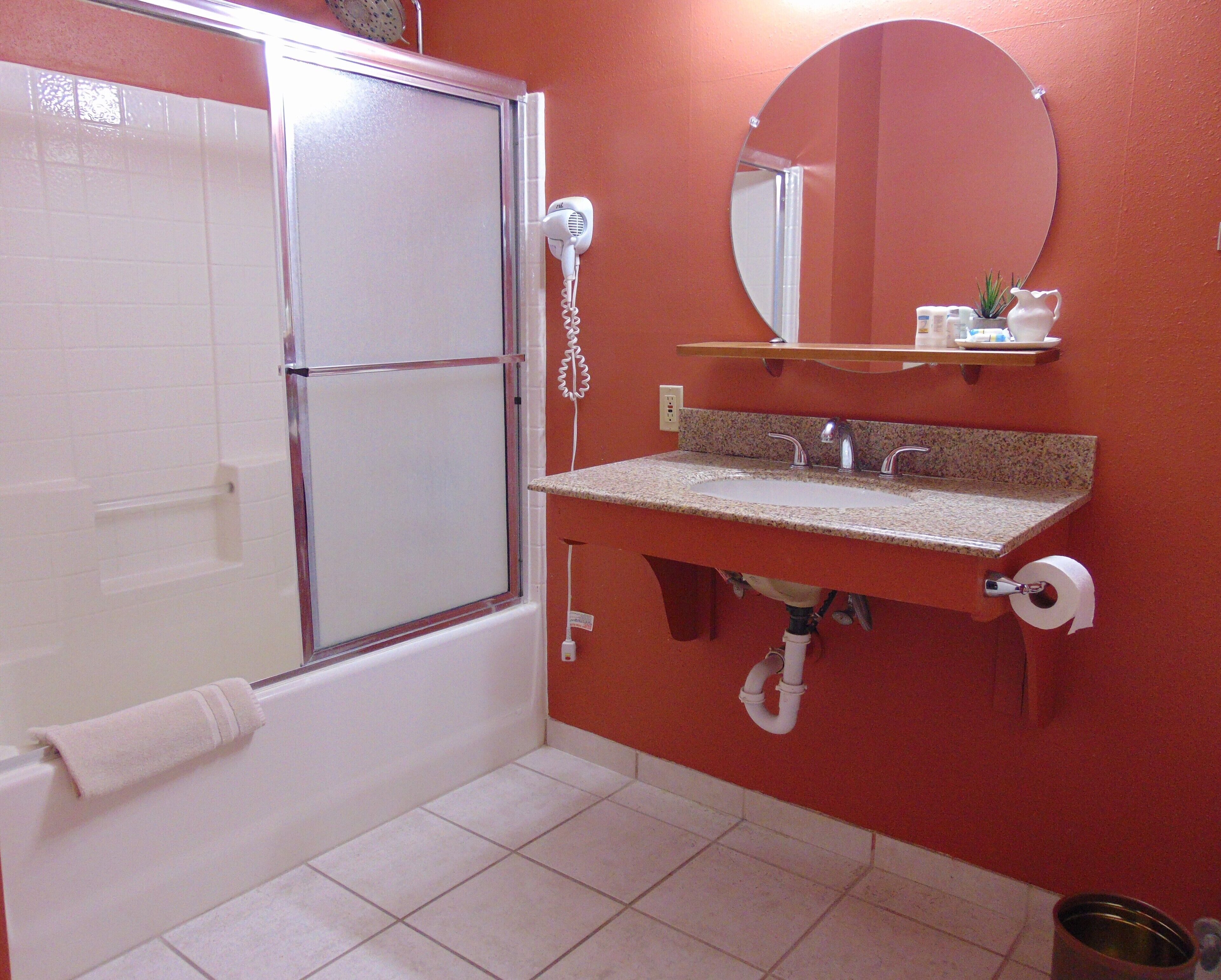 Une salle de bain avec une douche, un lavabo avec un miroir et des toilettes.