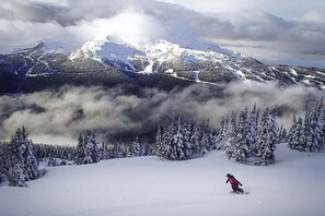 Un paisaje montañoso nevado con una persona practicando snowboard.