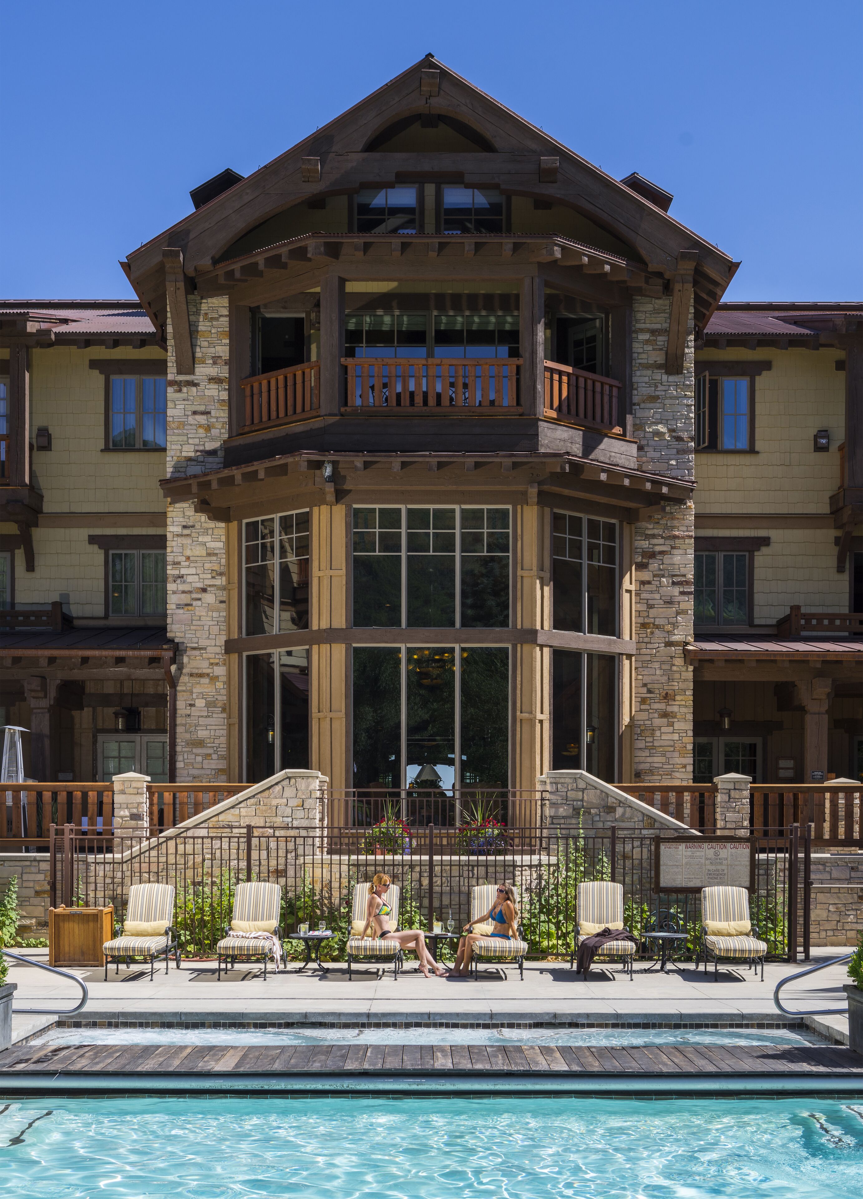 A large, multi-story building with a stone facade, large windows, and a balcony.