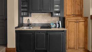 A kitchen with dark cabinets, a granite countertop, a sink, and a coffee maker.