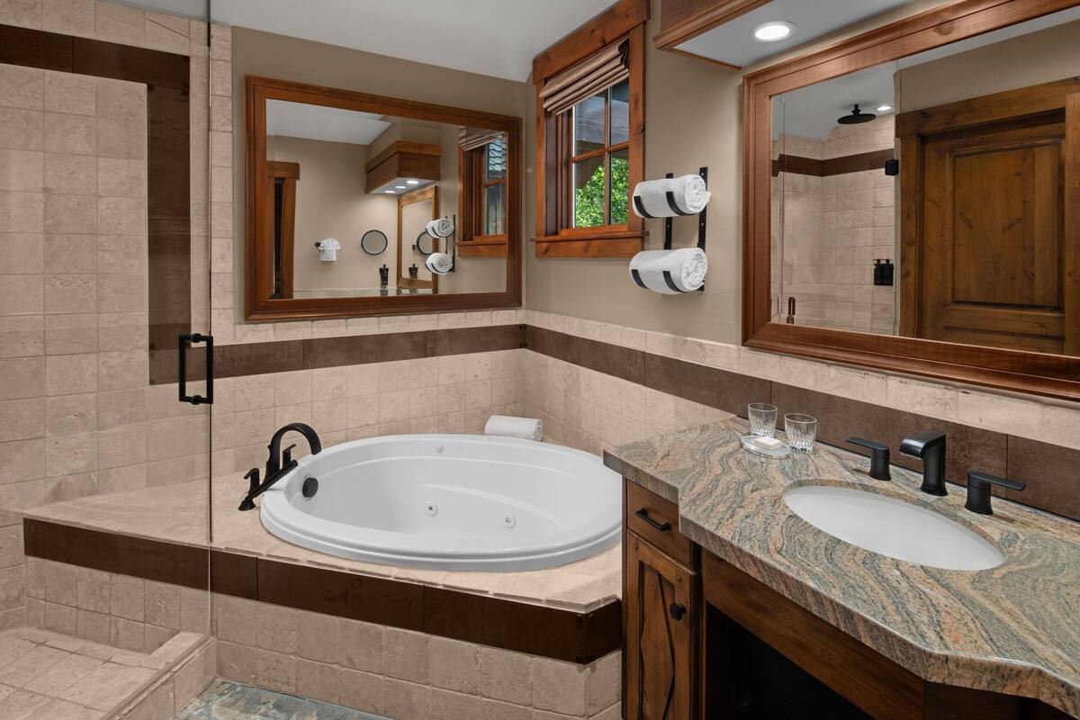 Un baño moderno con una bañera independiente, un tocador con lavabo y un espejo grande.
