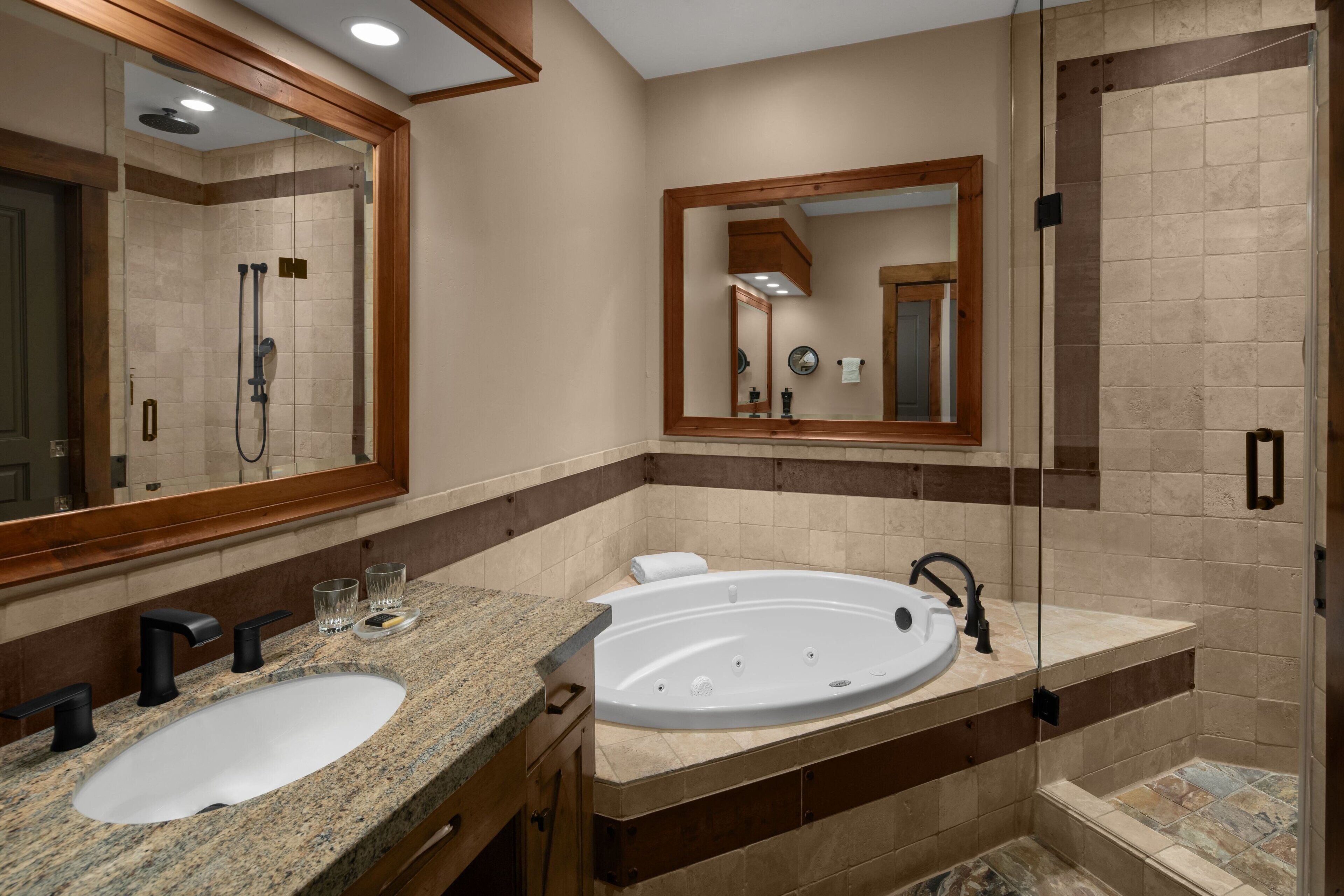 A bathroom with a double sink, a large bathtub, and a walk-in shower.