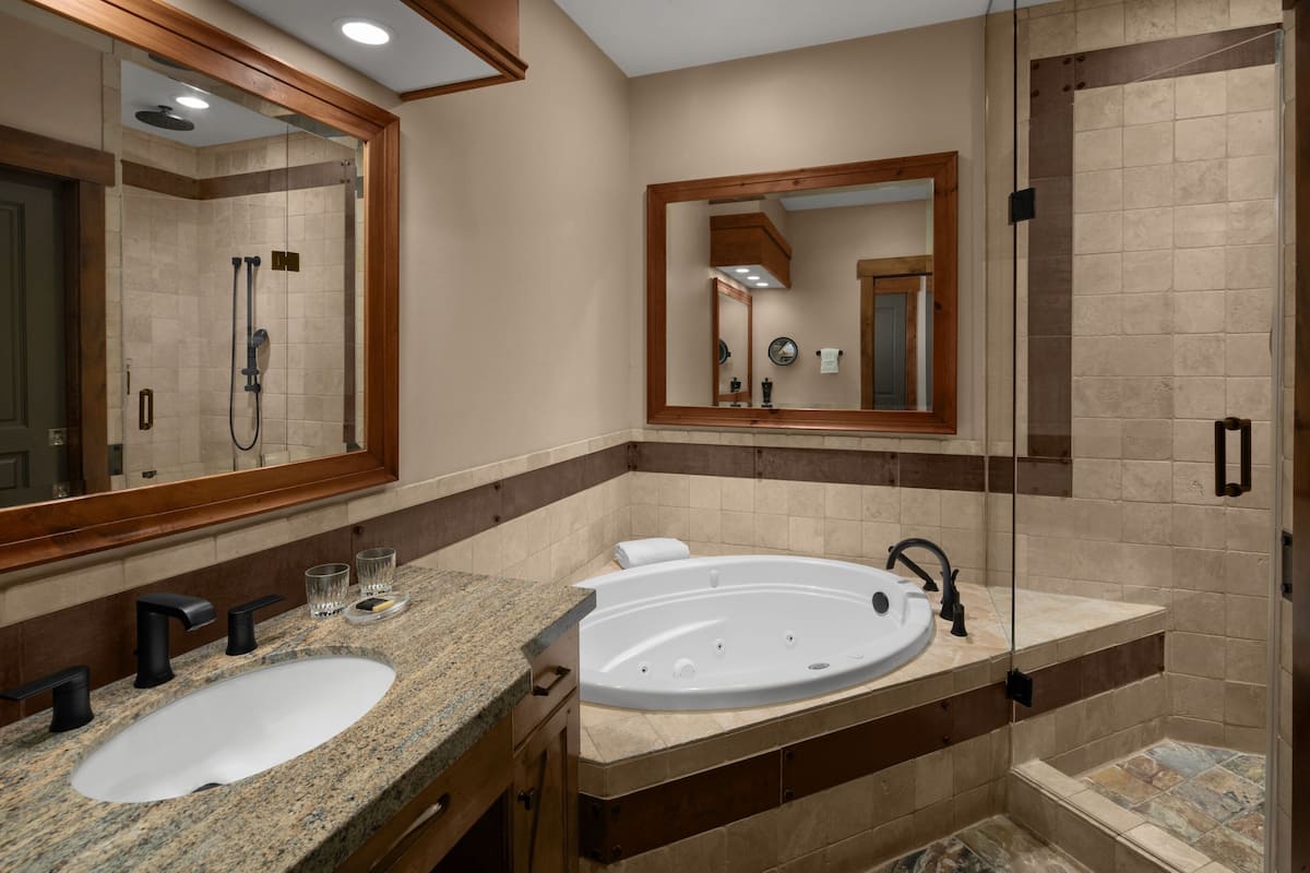 Un baño con lavamanos doble, una bañera grande y una ducha a ras de suelo.