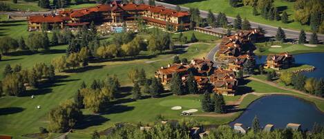 A large resort with multiple buildings, a golf course, and a lake.