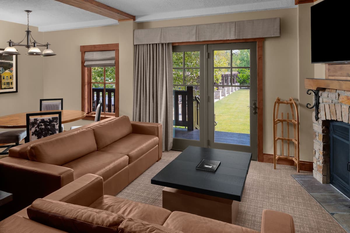 A living room with a sofa, a coffee table, a fireplace, and a view of the outdoors.