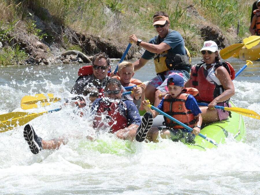 Eine Gruppe von Menschen in einem grünen Floß, das einen Fluss befährt.