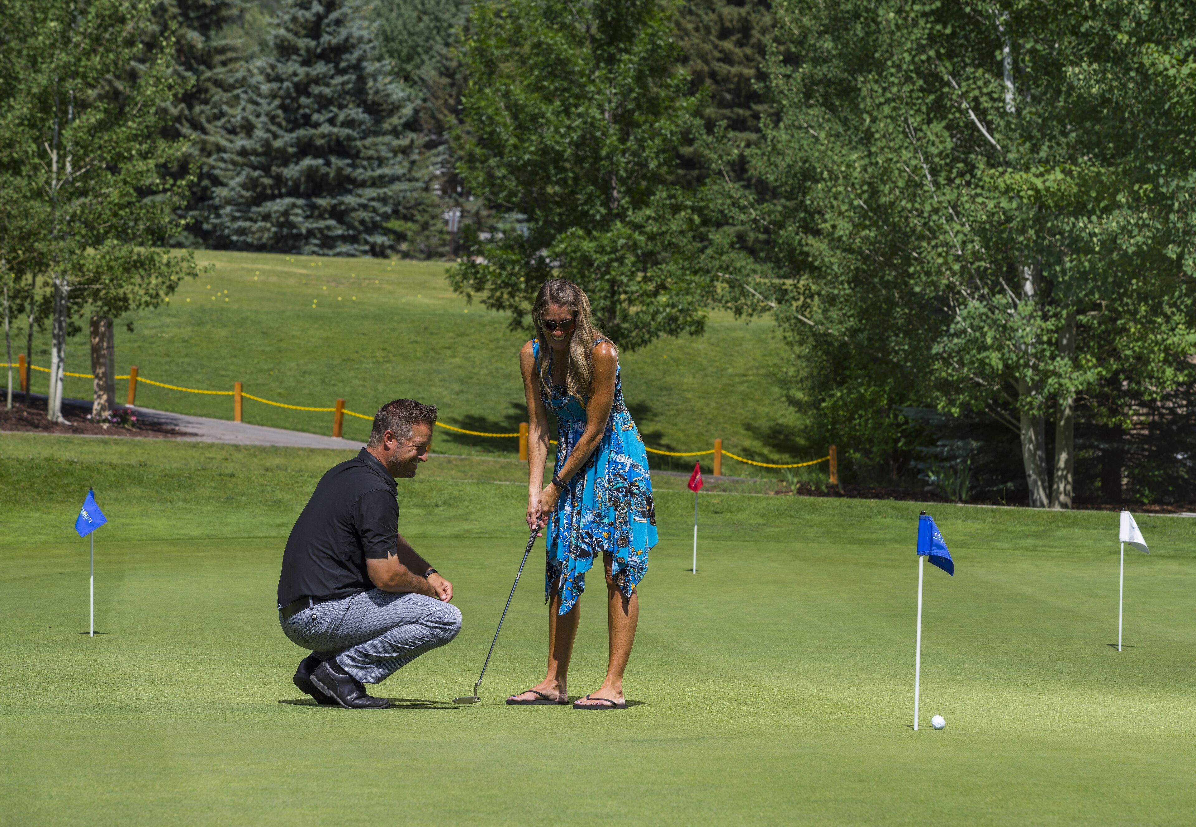 Un homme et une femme sur un terrain de golf, avec des drapeaux et un mât de drapeau.