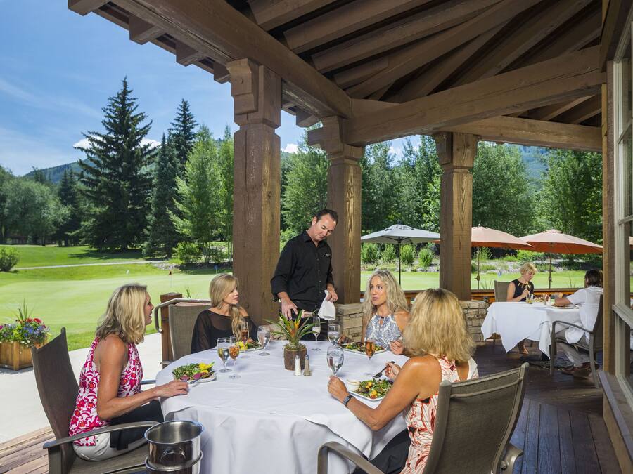 A covered outdoor dining area with a view of a golf course.