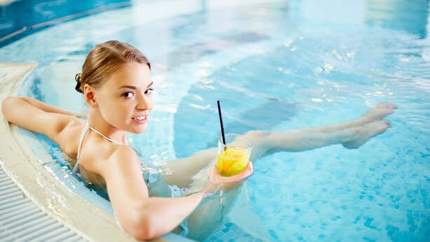 Una persona en una piscina sosteniendo una bebida.