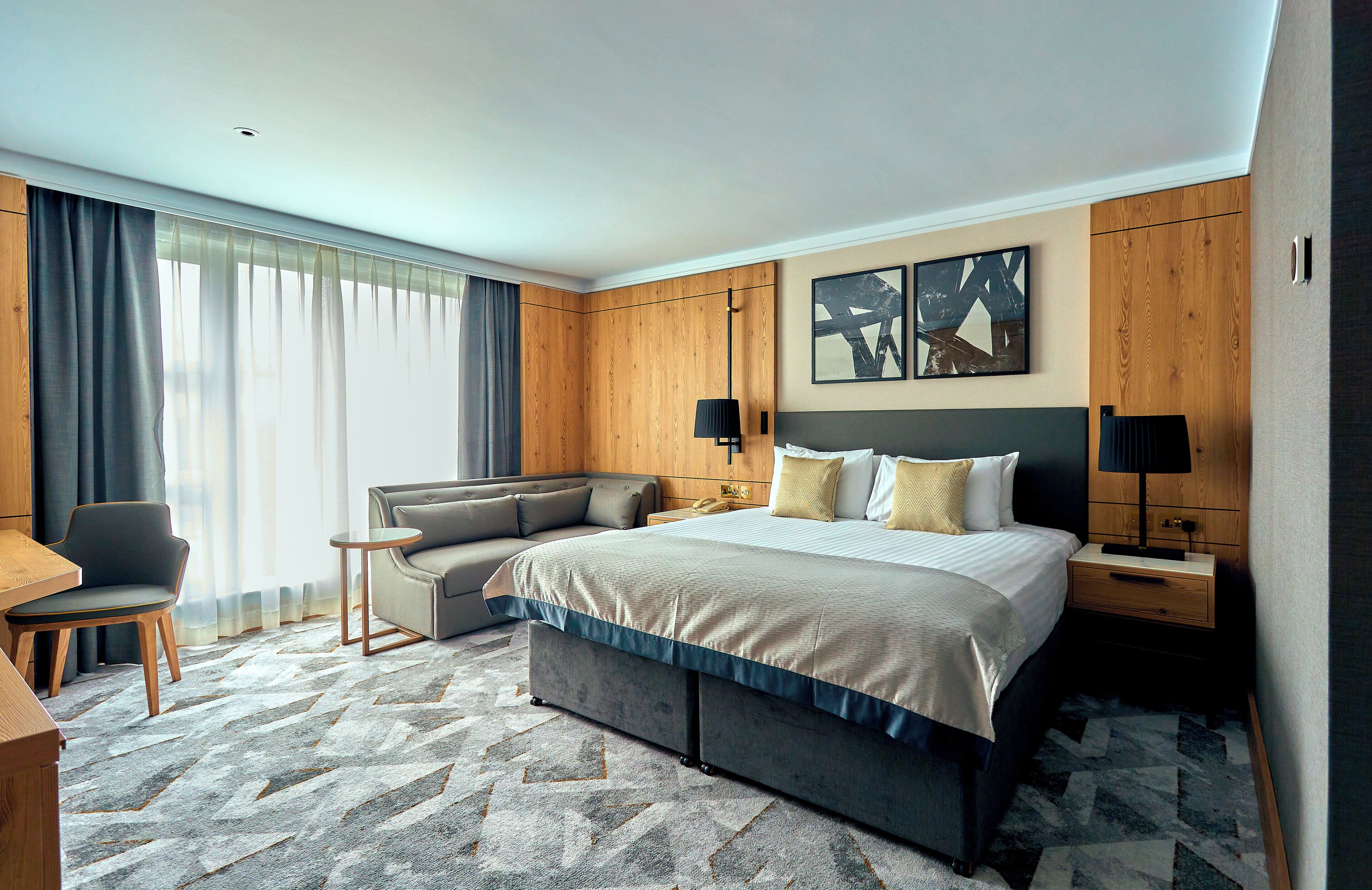 A hotel room with a bed, a sofa, a desk, and a chair.