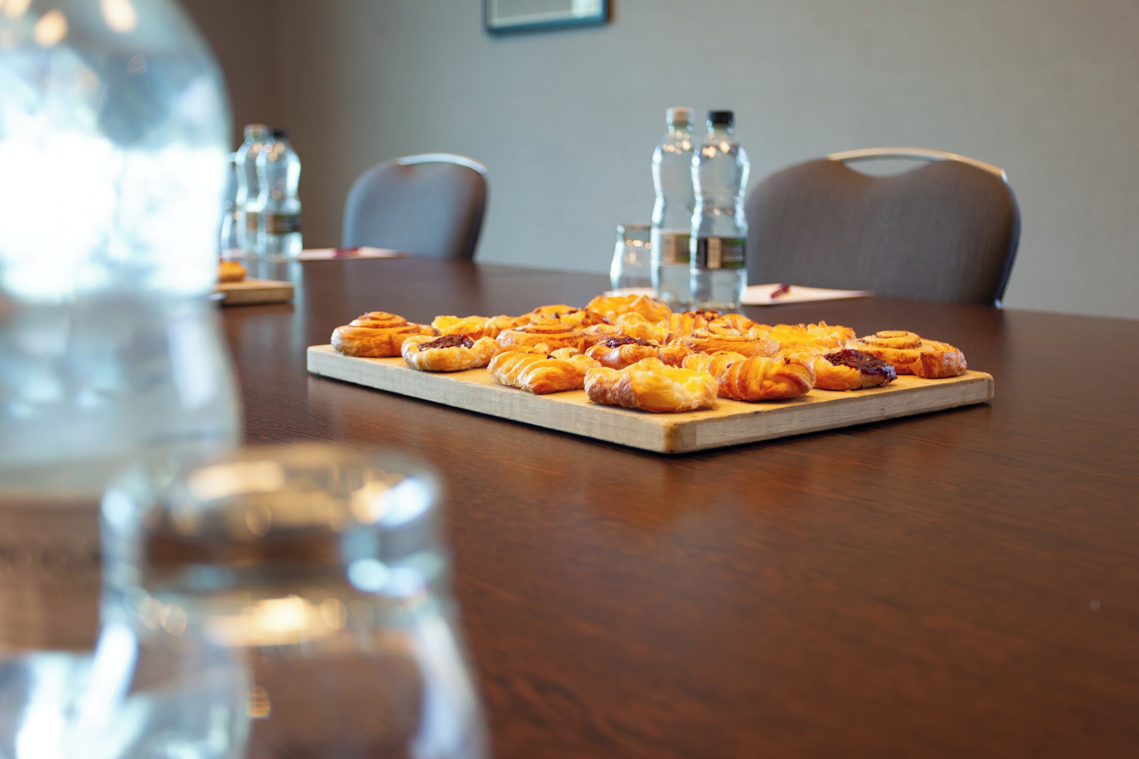 A wooden table with a tray of pastries.