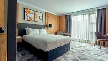 Une chambre d’hôtel avec un grand lit, un bureau, une chaise et une fenêtre avec des rideaux.