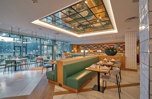 A modern restaurant interior with a high ceiling, glass panels, and a view of the cityscape. - Crowne Plaza Hotel Marlow by IHG (Marlow)