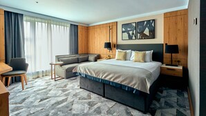 Una habitación de hotel moderna con una cama grande, un sofá, un escritorio y un televisor.