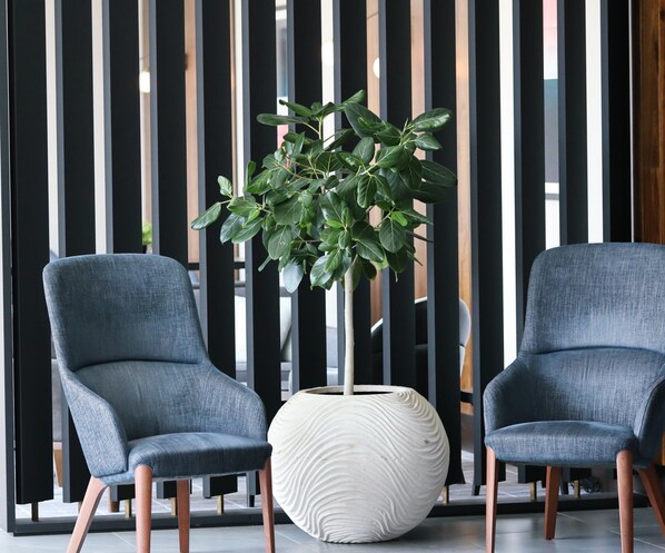 Two modern chairs with wooden legs and a large white vase with a textured design. - Crowne Plaza Hotel Marlow by IHG (Marlow)