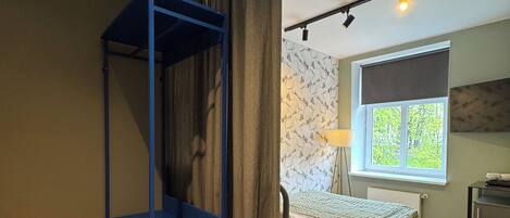 Una habitación con literas, un ventanal con vistas y un escritorio con lámpara.