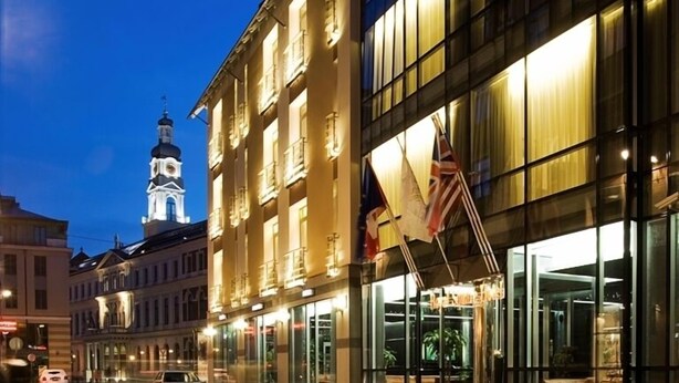 A hotel with a modern facade, large windows, and a prominent entrance with steps. - Royal Square Hotel & Suites (Riga)