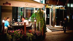 An outdoor dining area with tables and chairs, a potted plant, and a sign for Aldaris. - Royal Square Hotel & Suites (Riga)