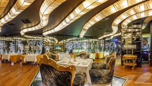 A restaurant with tables set for dining, ornate chairs, and a modern ceiling design. - Royal Square Hotel & Suites (Riga)