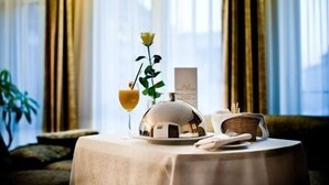 A table set with a glass of orange juice, a rose, a decorative bowl, and a small basket. - Royal Square Hotel & Suites (Riga)