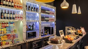 A bar area with shelves of bottled beverages, a selection of snacks, and a dessert display.