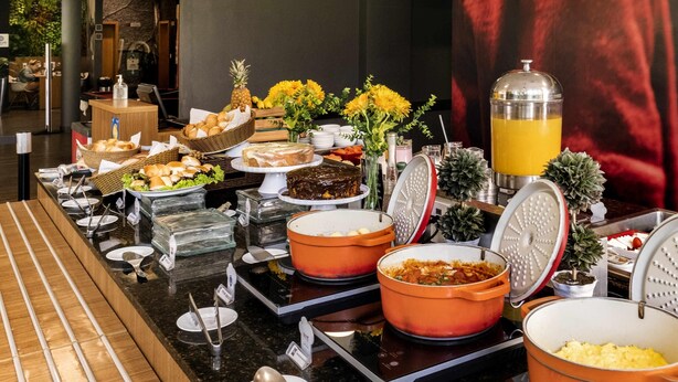 A buffet with various food items, including fruits, pastries, and a juice dispenser.