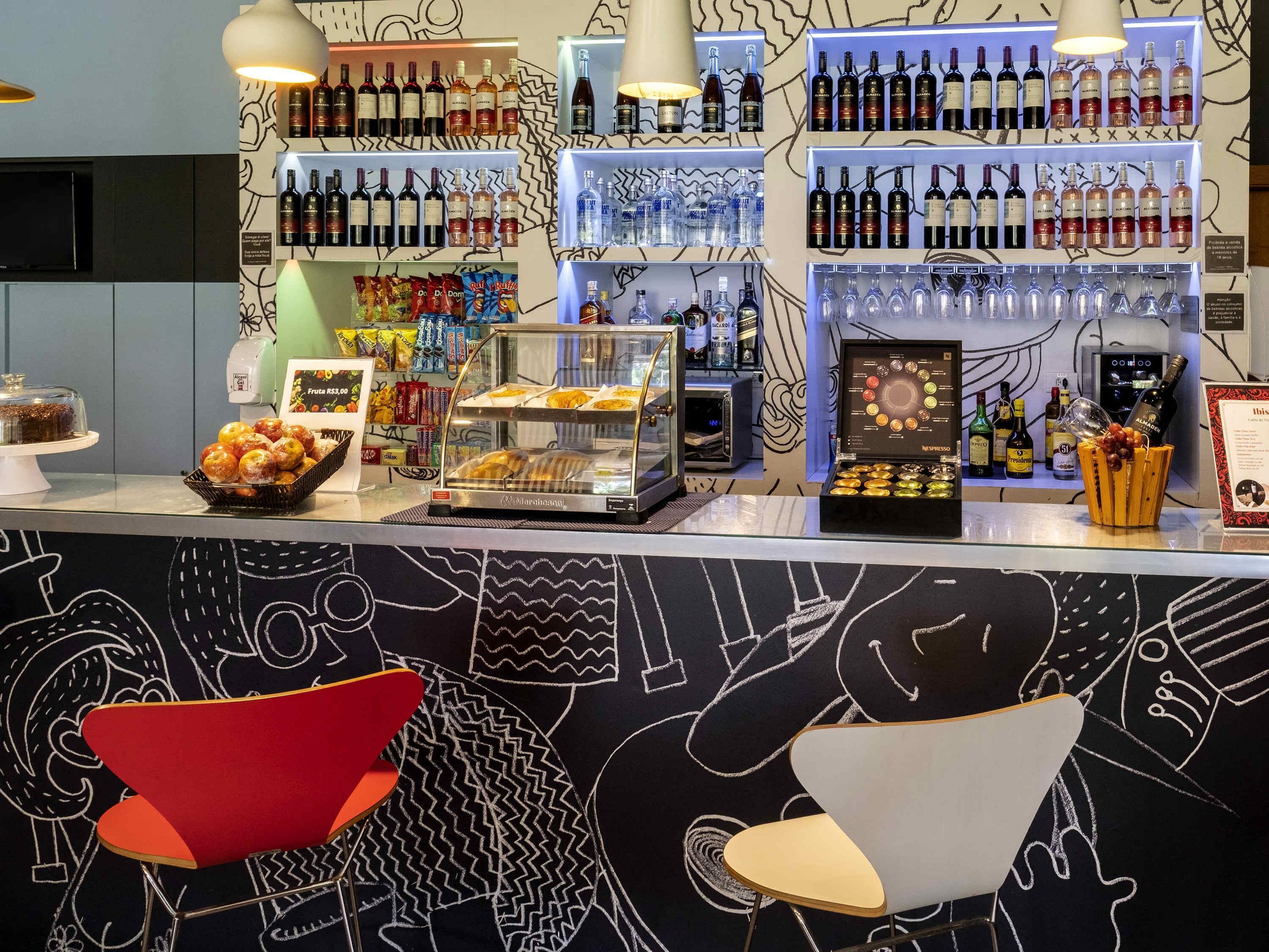 A bar area with shelves of wine bottles, a display of snacks, and a coffee machine.