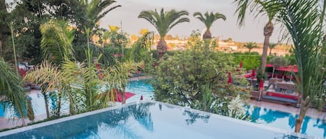 Una piscina al aire libre, sombrillas, tumbonas