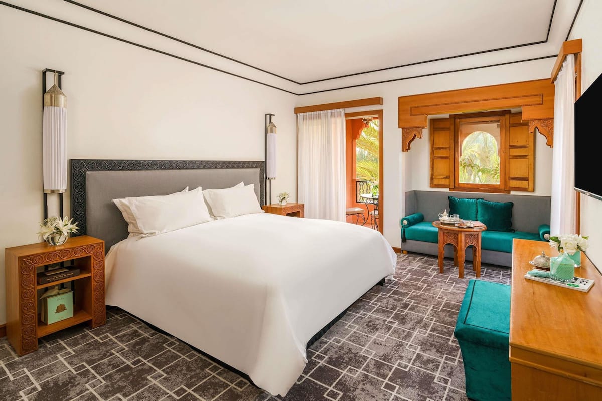 A hotel room with a large bed, a sofa, a small table, and a TV.