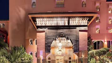 A hotel entrance with a traditional archway, a covered walkway, and a well-maintained garden.