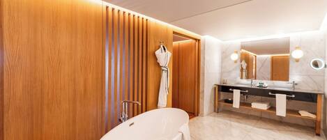 A modern bathroom with a freestanding bathtub, a vanity with a mirror, and wooden paneling on the walls.