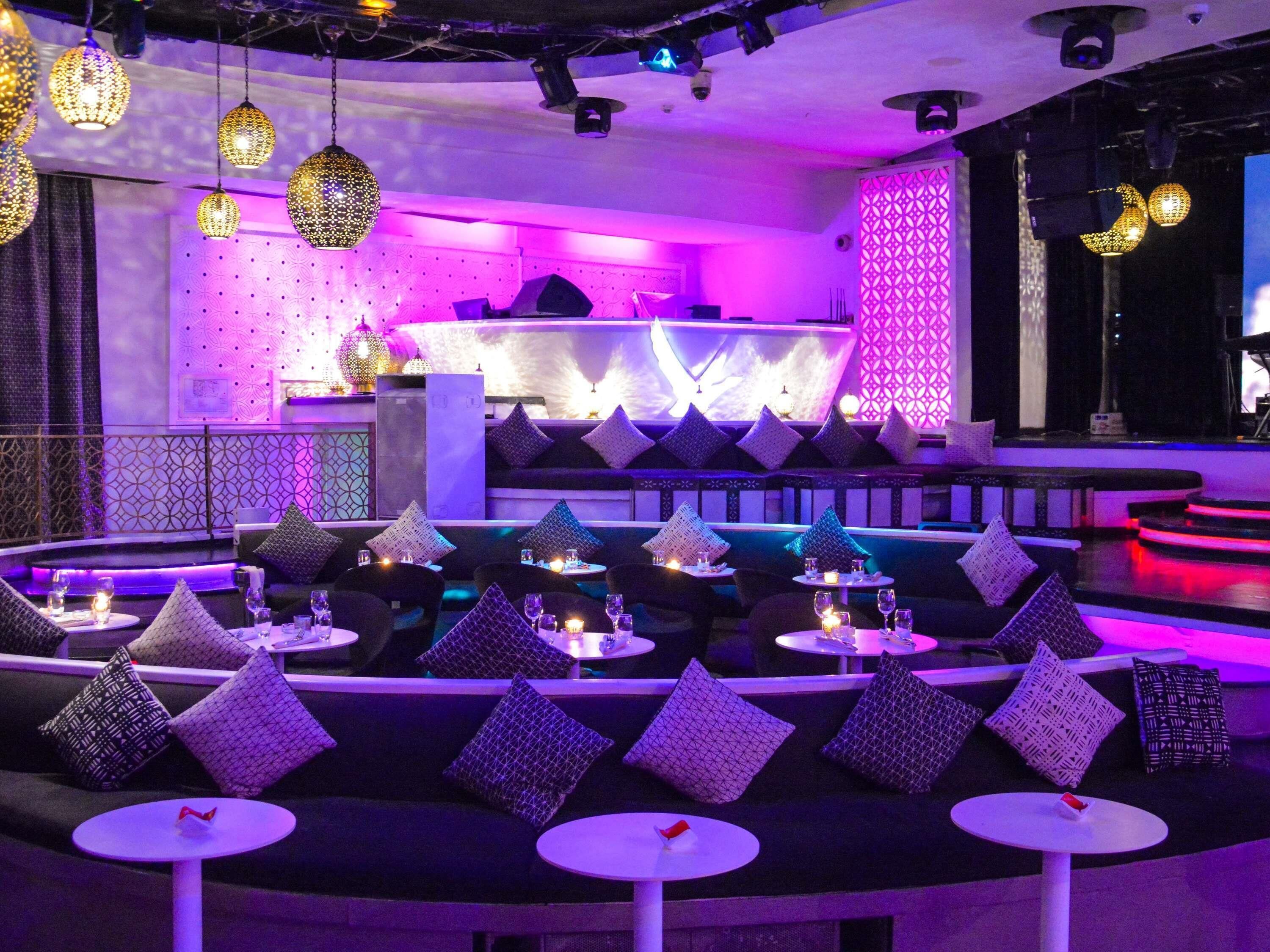 A modern lounge area with round tables, cushioned seating, and decorative lighting.