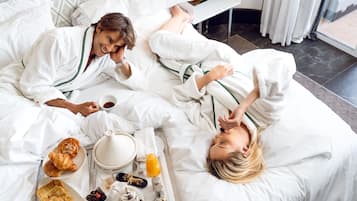 Una camera d'albergo con un letto, un vassoio per la colazione e una finestra con tende.