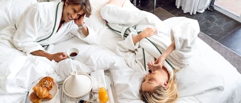 Habitación de hotel con cama, bandeja de desayuno y ventana con cortinas.