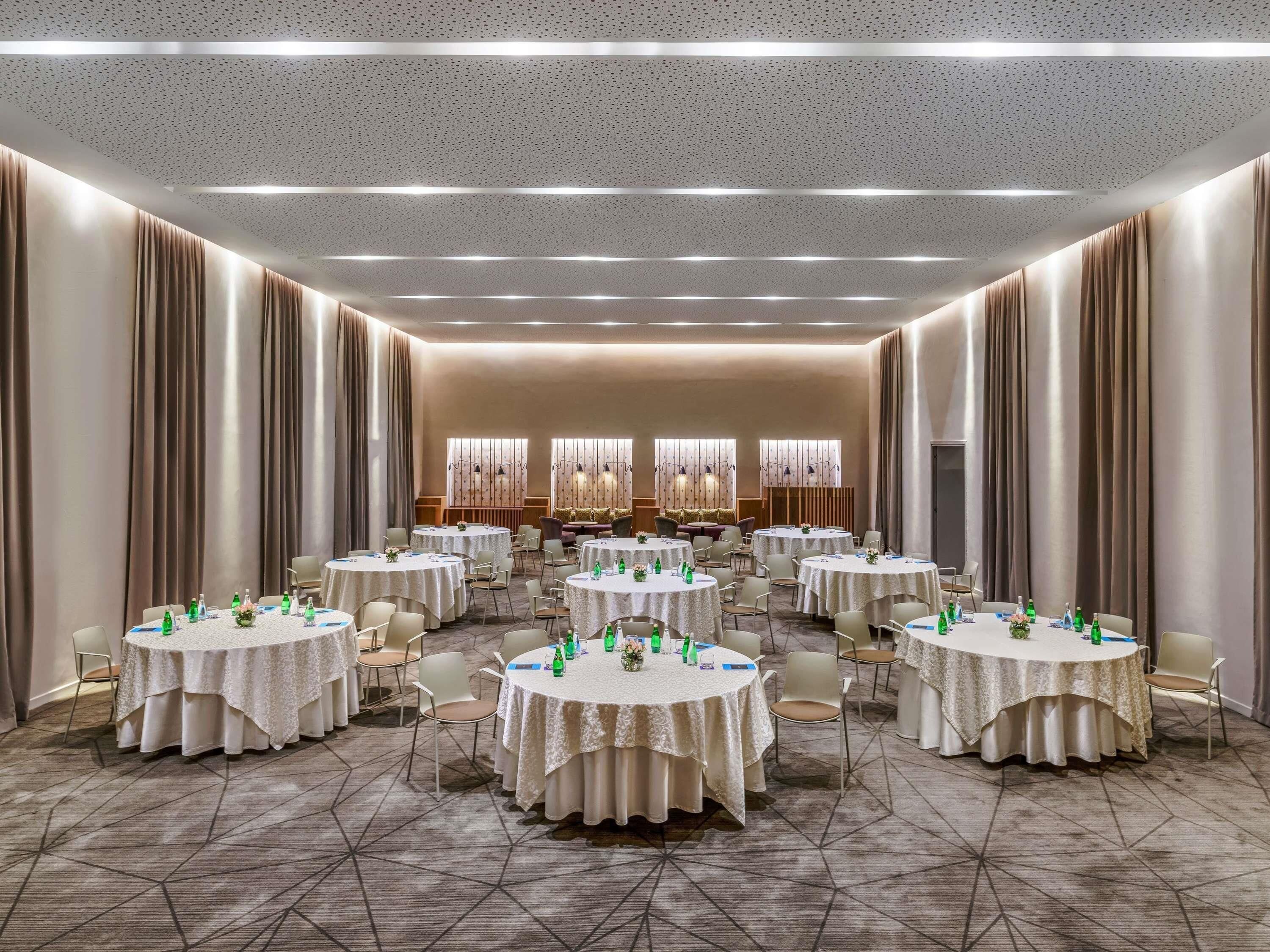 A conference room with round tables, chairs, and a patterned carpet.